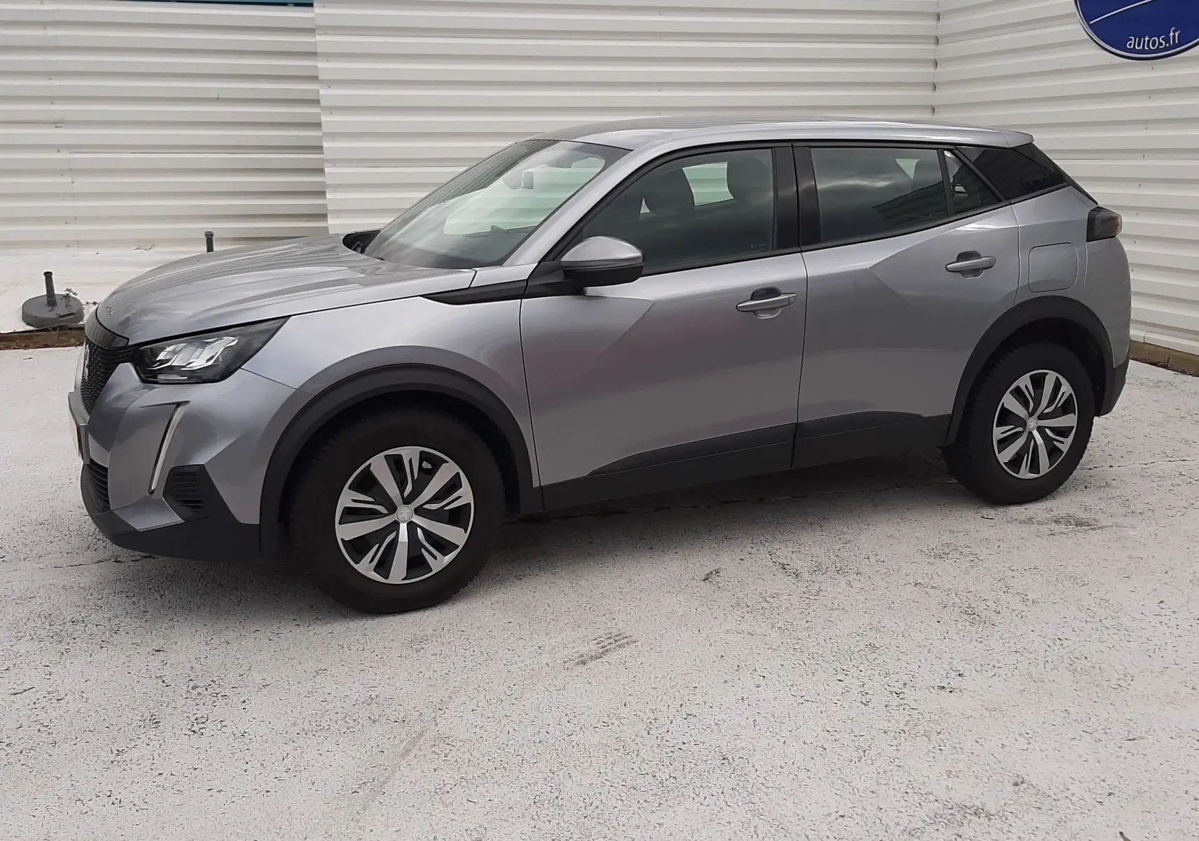 Vue 3/4 avant droit d'un Peugeot 2008 gris Artense avec jantes alliage et détails noirs contrastants.