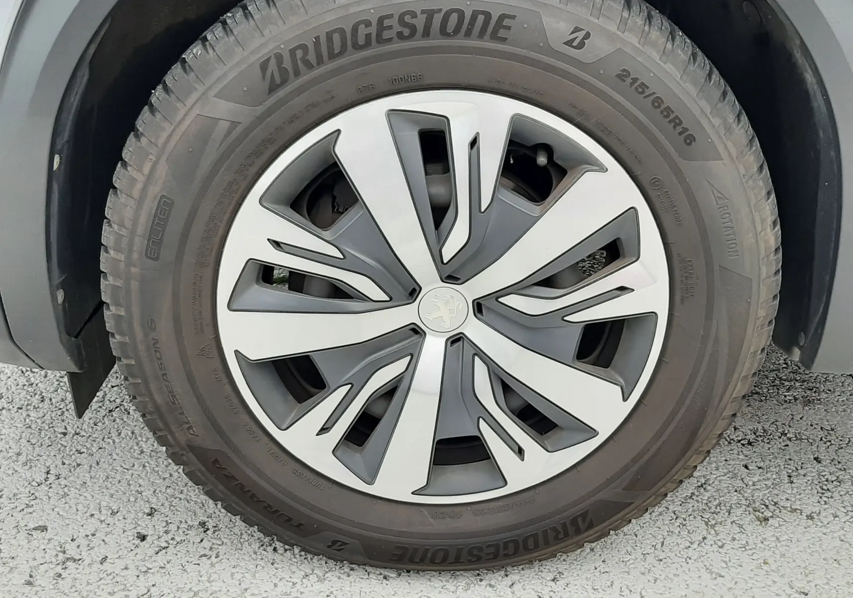Gros plan sur la roue avant gauche d’un Peugeot 2008 gris Artense, jante alliage au design moderne et pneu Bridgestone.