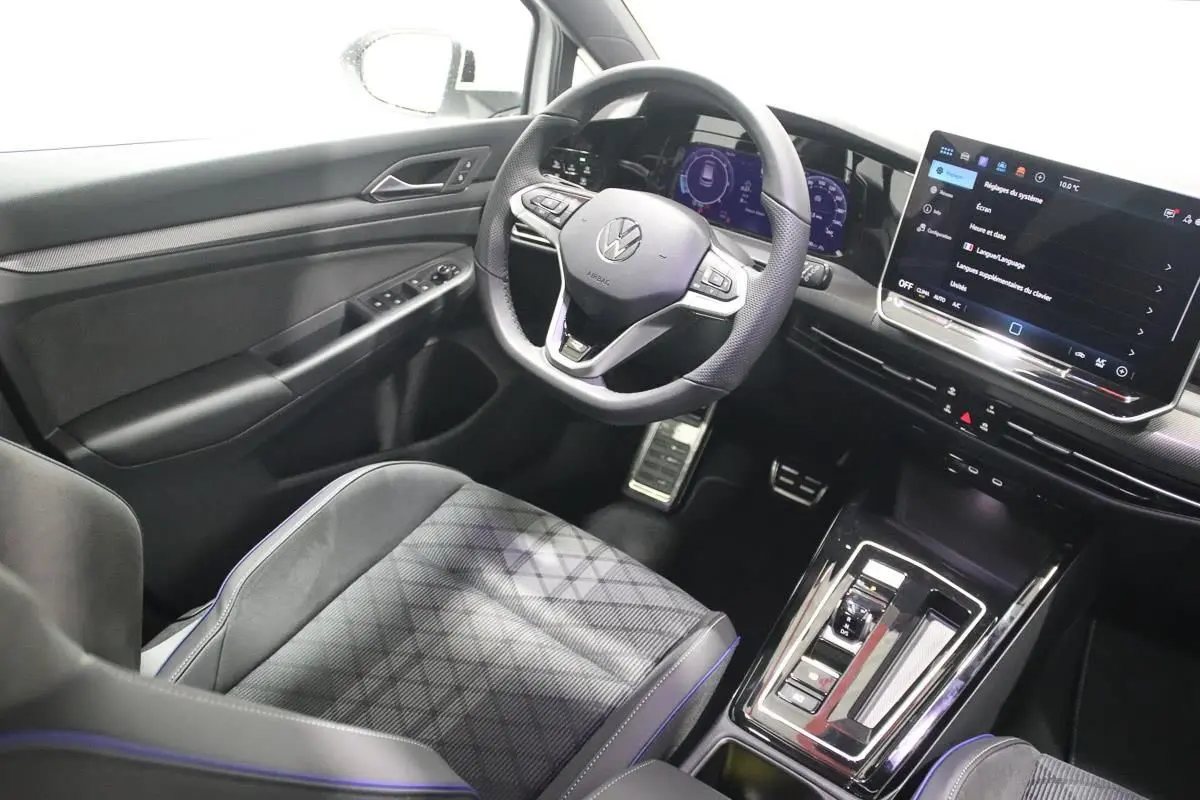 Vue intérieure côté conducteur de la Volkswagen Golf 2.0 TDI 150 DSG R-Line avec volant cuir et écran tactile central.