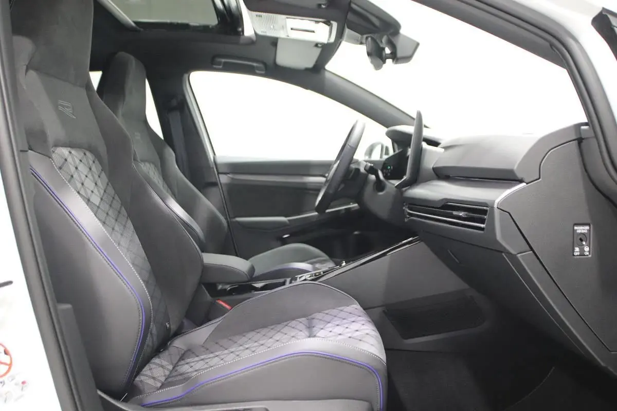 Vue intérieure côté gauche de la Volkswagen Golf 2.0 TDI R-Line blanche avec sièges sport et toit panoramique.