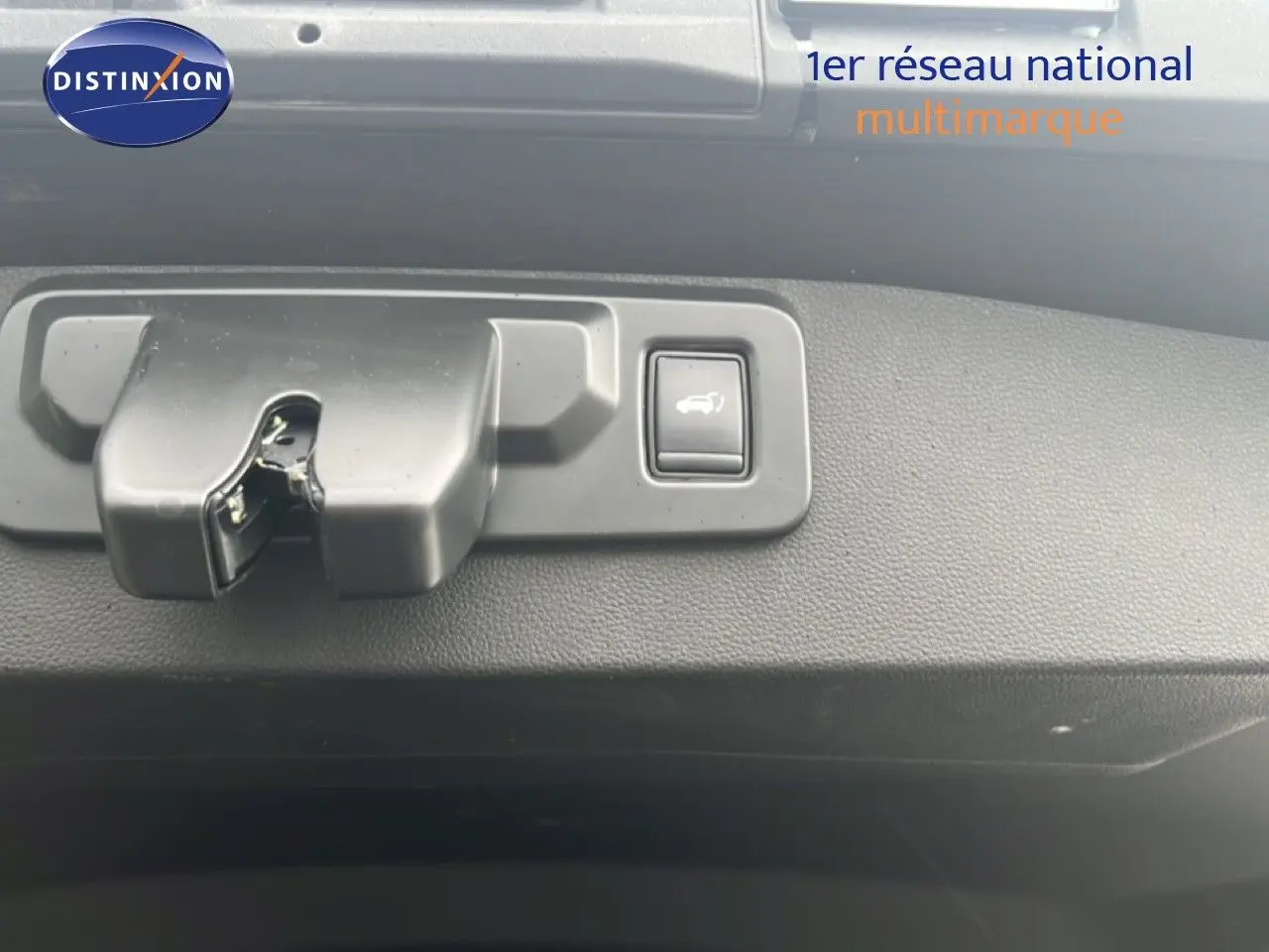 Gros plan sur le mécanisme d'ouverture du hayon avec bouton de déverrouillage, intérieur noir du Renault Symbioz.