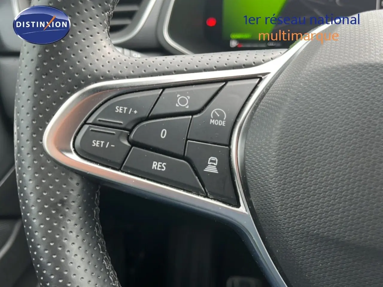 Gros plan sur les commandes à gauche du volant perforé du Renault Symbioz gris Cassiopée, boutons de régulateur et assistance.