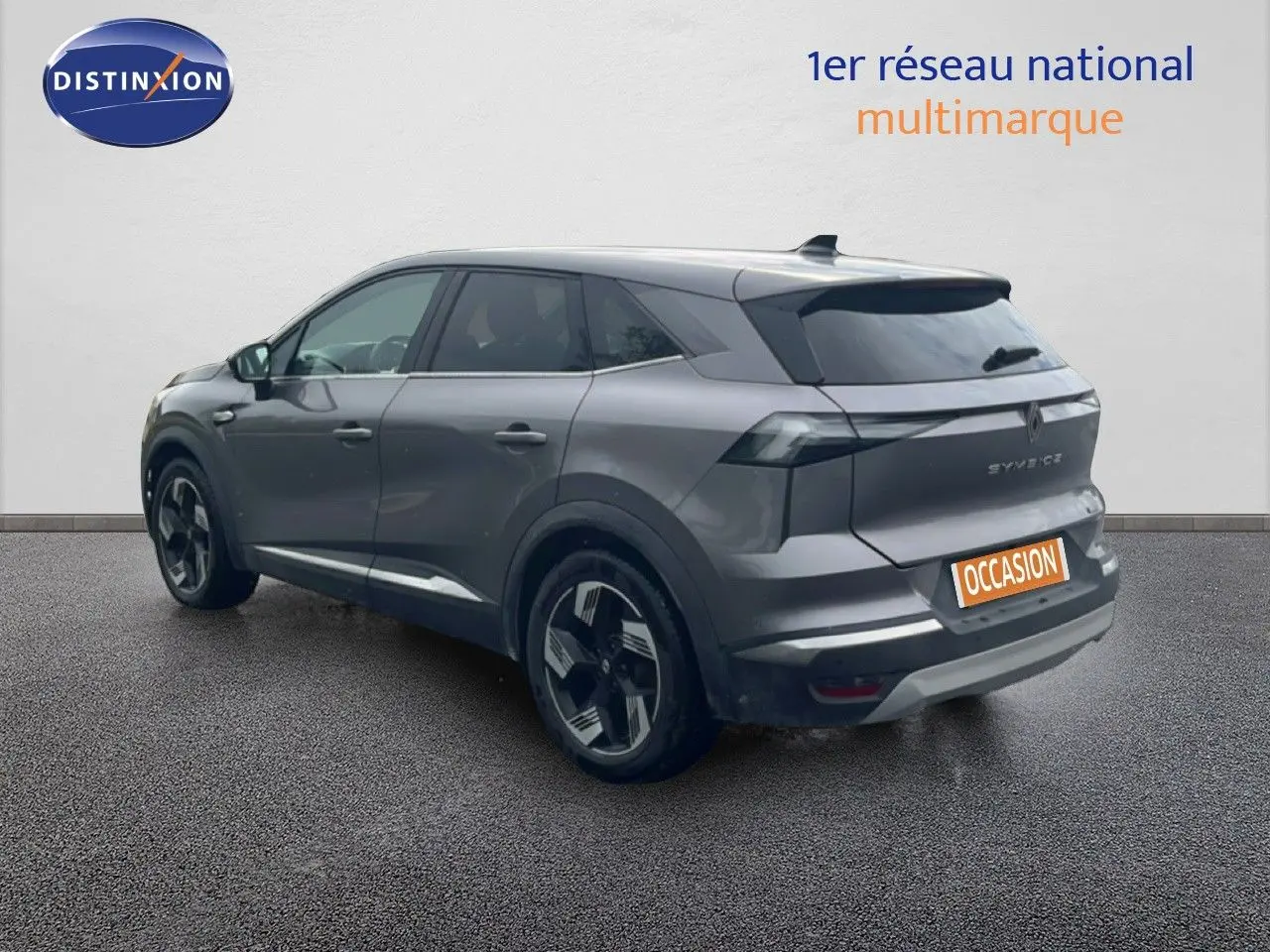 Vue 3/4 arrière droite d’un Renault Symbioz gris cassiopée métallisé avec jantes noires et grises, sur fond neutre.