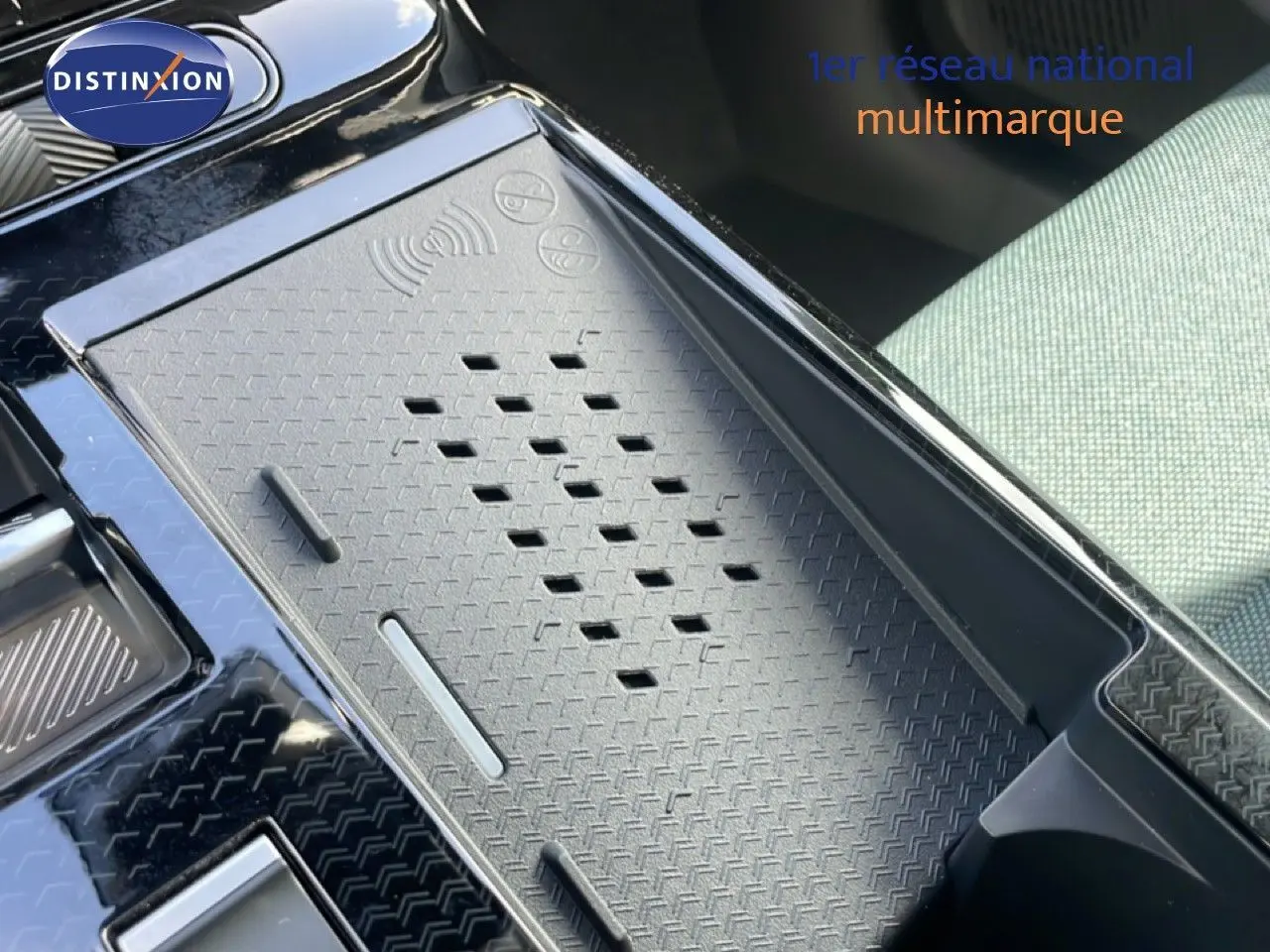 Gros plan sur le chargeur sans fil et la console centrale noire du Citroën C5 Aircross Hybrid 2026, siège vert Astoria visible.