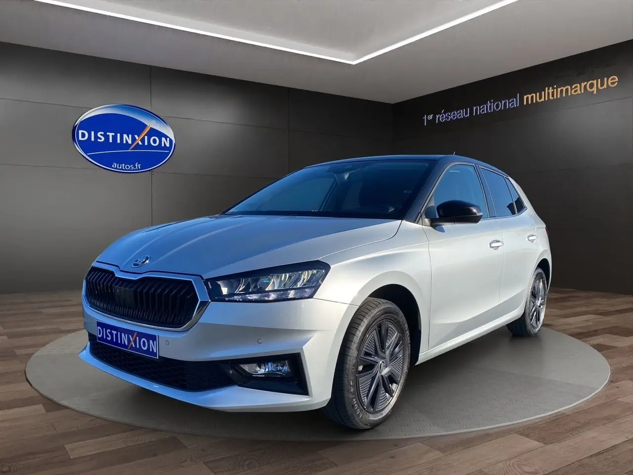 Vue 3/4 avant d'une Skoda Fabia 2024 gris clair avec toit noir et jantes au design moderne.