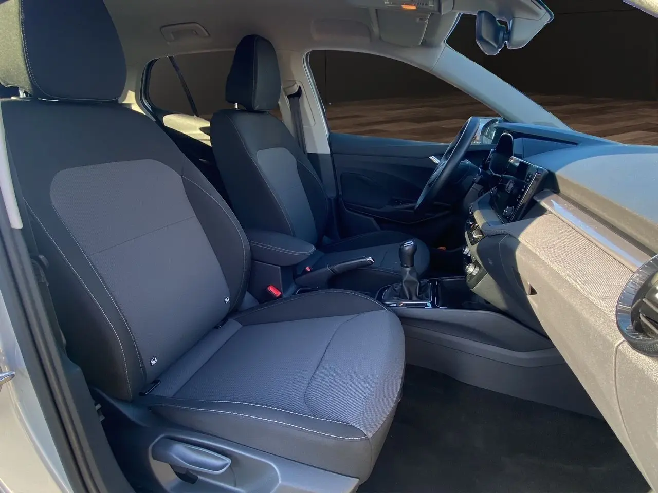 Vue intérieure côté gauche de la Skoda Fabia 2024, sièges tissu gris avec surpiqûres et console centrale noire.