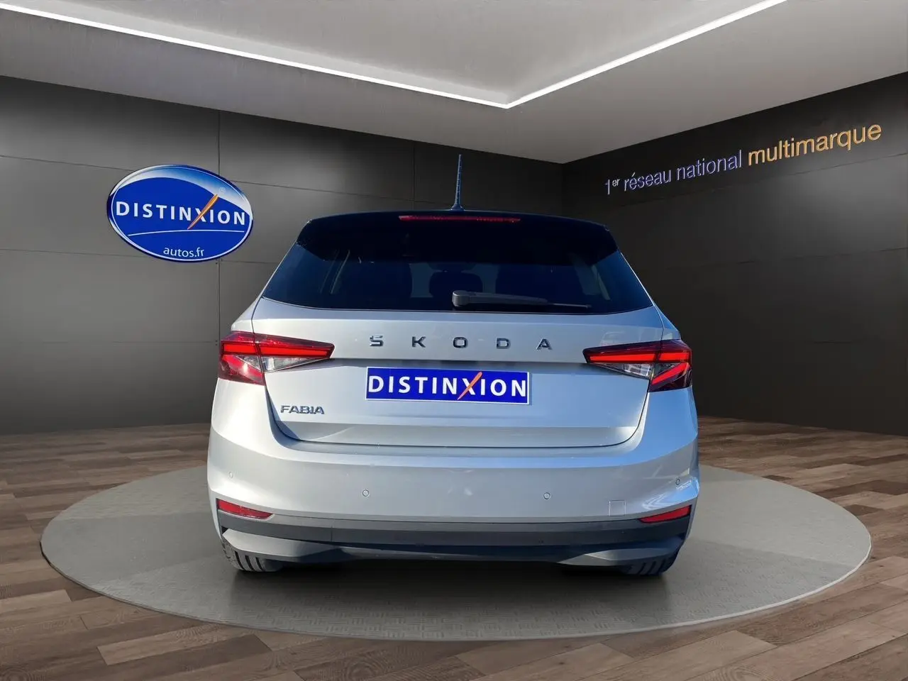 Vue arrière d'une Skoda Fabia 2024 gris clair avec toit noir, feux LED et logo distinctif sur fond showroom.