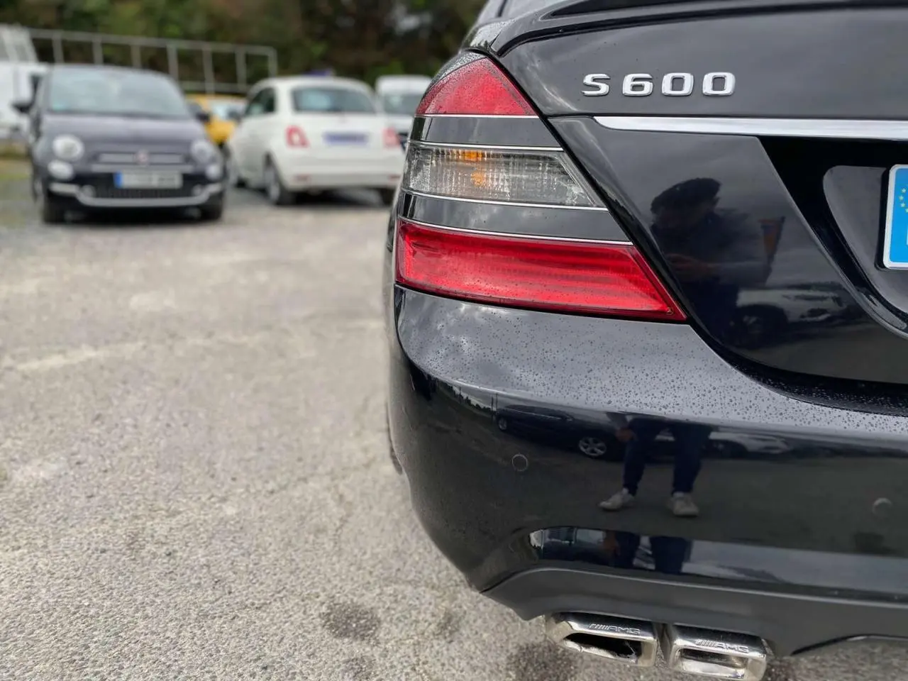 Gros plan sur l'arrière droit noir d'une Mercedes Classe S 600 L avec feux et double sortie d'échappement AMG visibles.