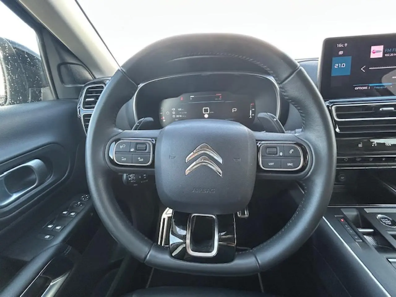 Vue intérieure centrée sur le volant cuir du Citroën C5 Aircross 2022 avec tableau de bord numérique et écran tactile.