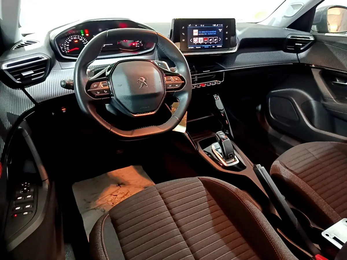 Intérieur du Peugeot 2008 2021 vu côté conducteur, volant cuir multifonctions et écran tactile central allumé.