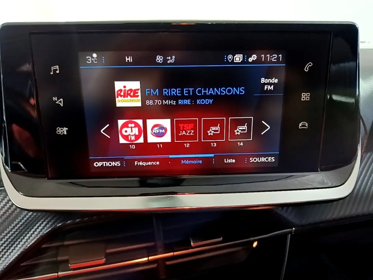 Écran tactile central du tableau de bord du Peugeot 2008 gris clair, affichant les stations radio FM.
