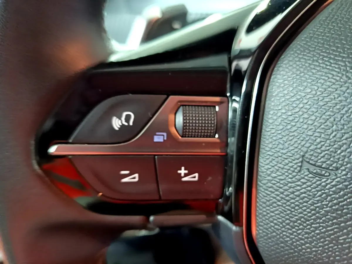 Gros plan sur les commandes multifonctions du volant cuir noir du Peugeot 2008, avec boutons de volume et appel.