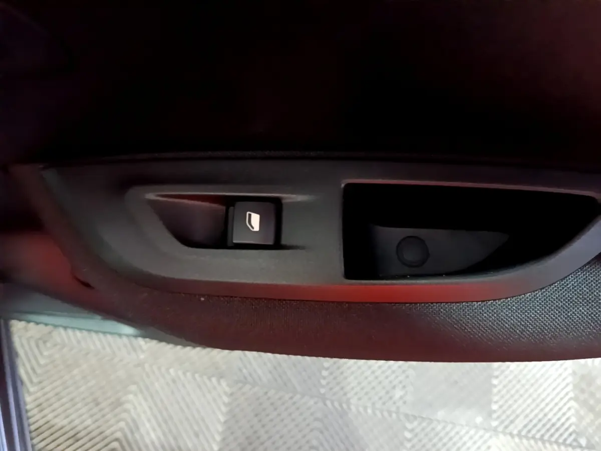 Bouton de commande de lève-vitre côté conducteur sur la porte intérieure d’un Peugeot 2008 gris clair.