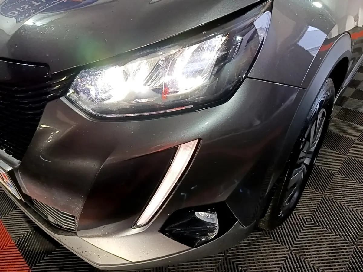 Gros plan sur l'avant droit gris clair du Peugeot 2008, mettant en valeur le phare LED allumé et le feu antibrouillard.
