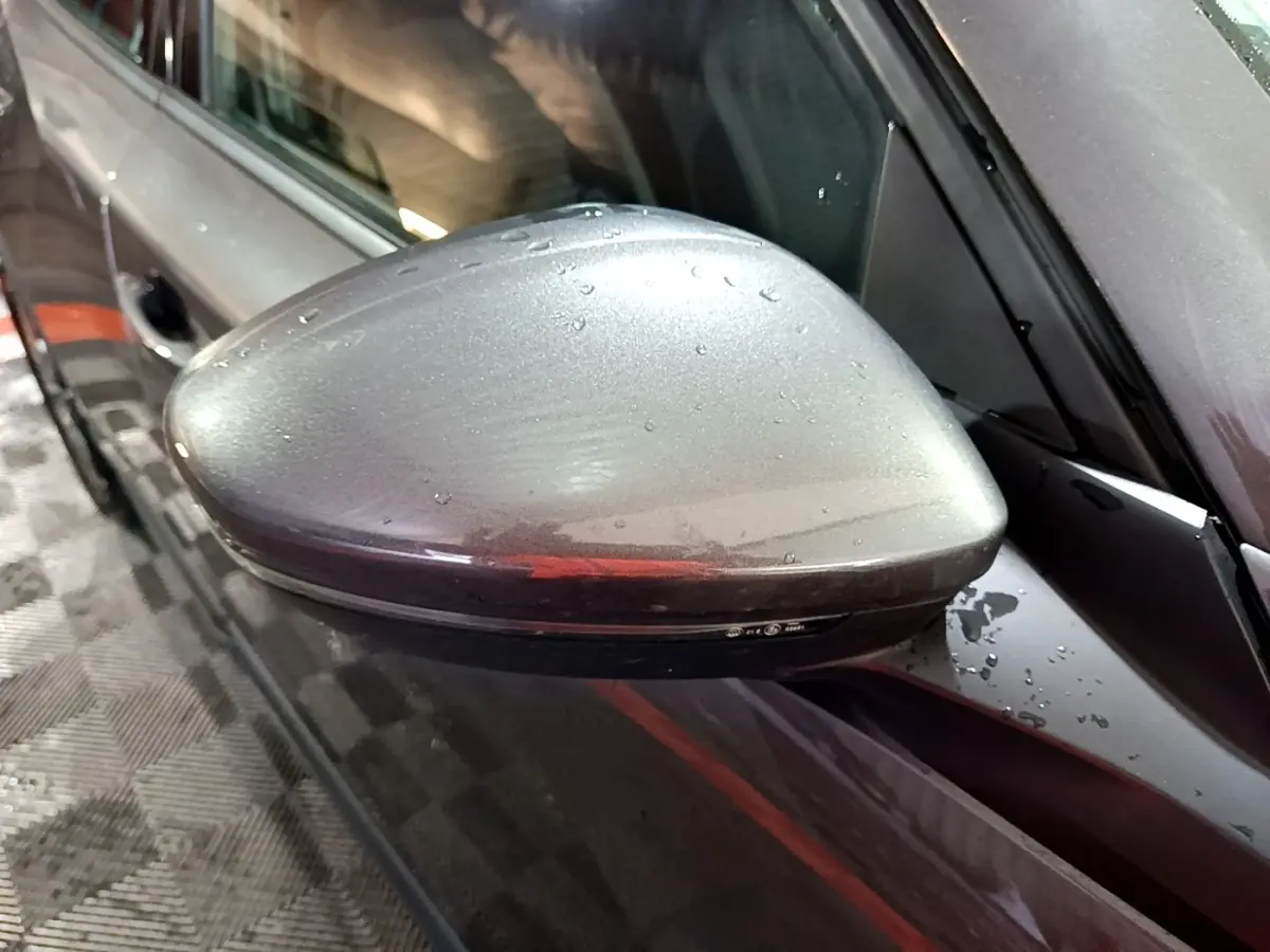 Rétroviseur côté gauche gris clair de Peugeot 2008 2021 avec gouttes d'eau, vue rapprochée en légère plongée.