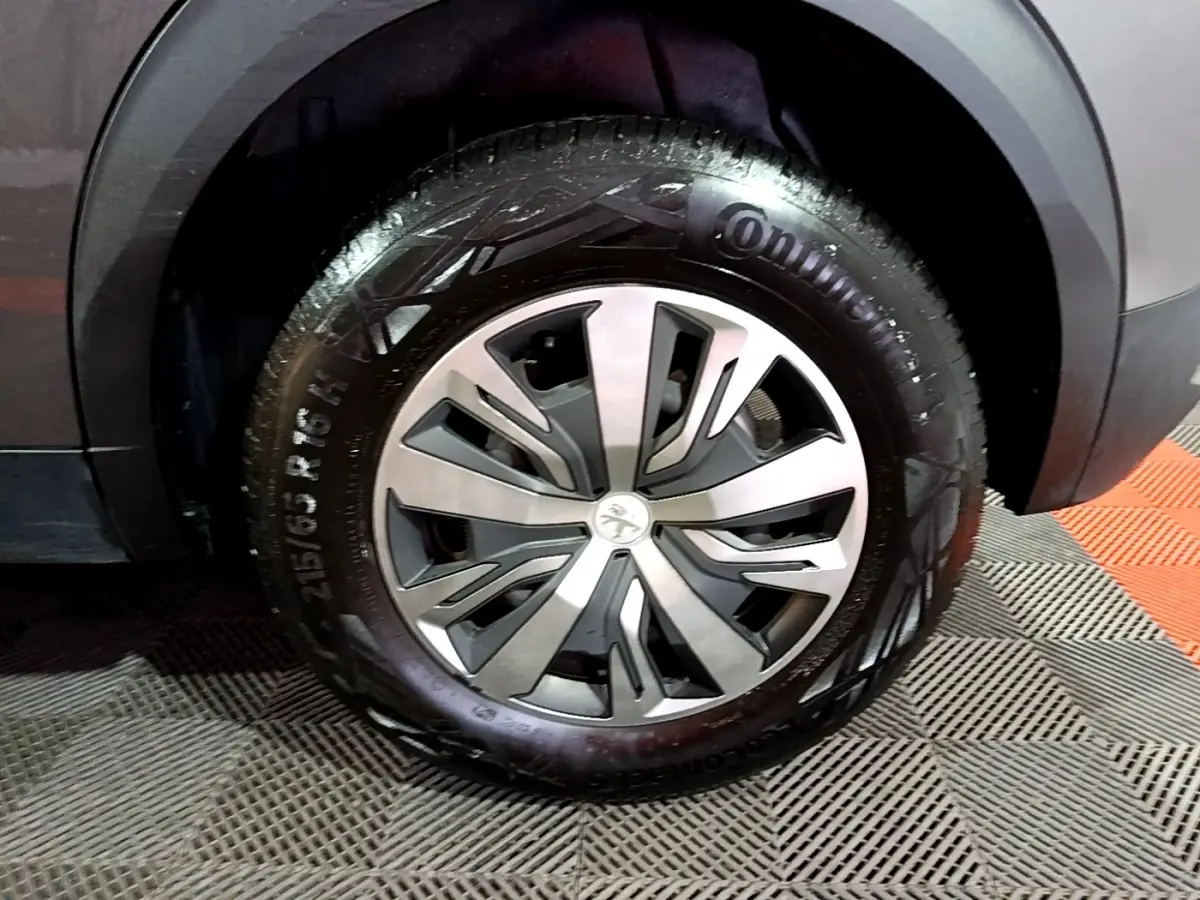 Gros plan sur la roue avant droite d’un Peugeot 2008 gris clair, avec jante alliage et pneu Continental visible.