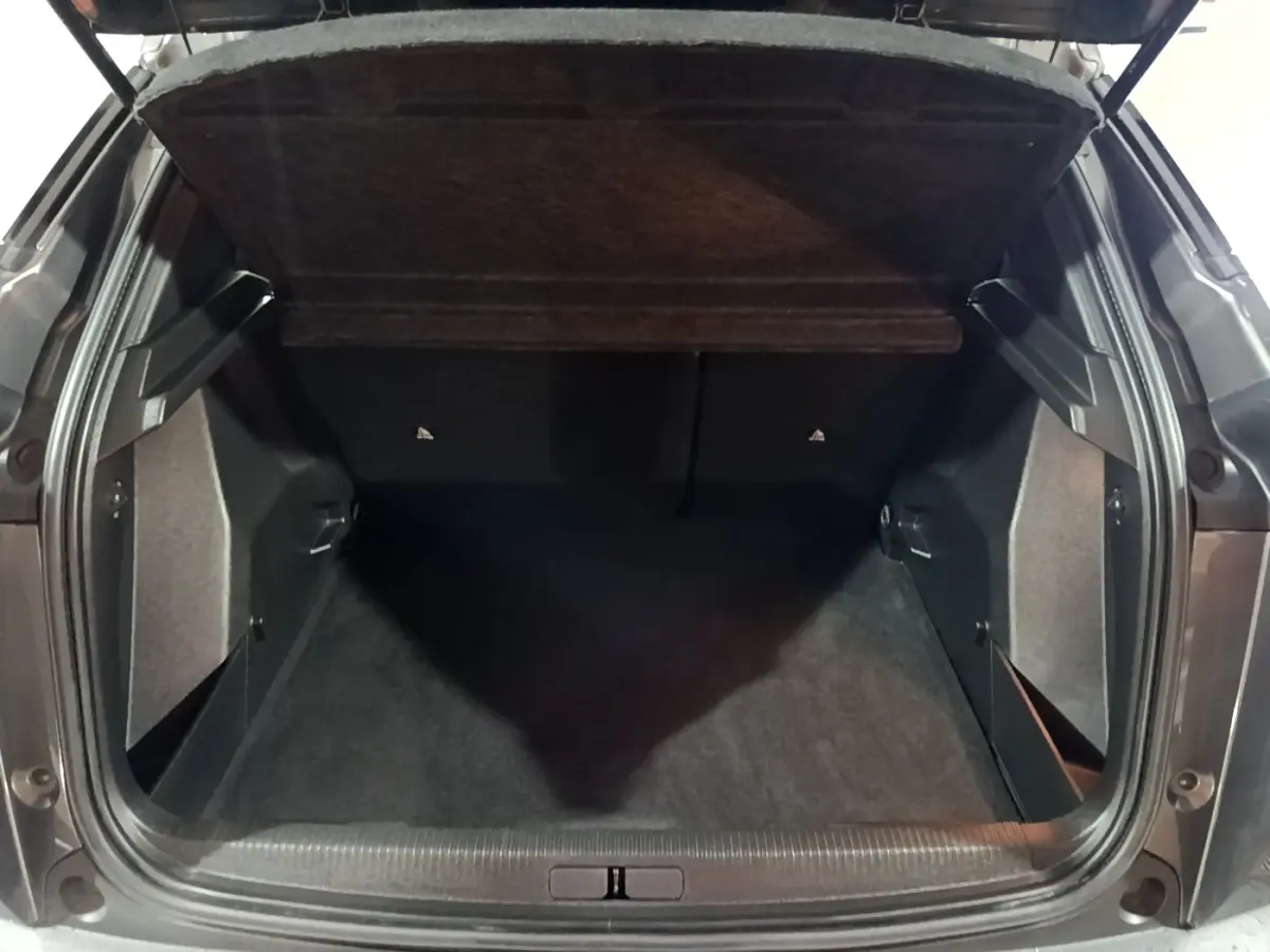 Coffre ouvert vu de l'arrière d'un Peugeot 2008 gris clair, montrant l'espace de chargement vide et la tablette cache-bagages.
