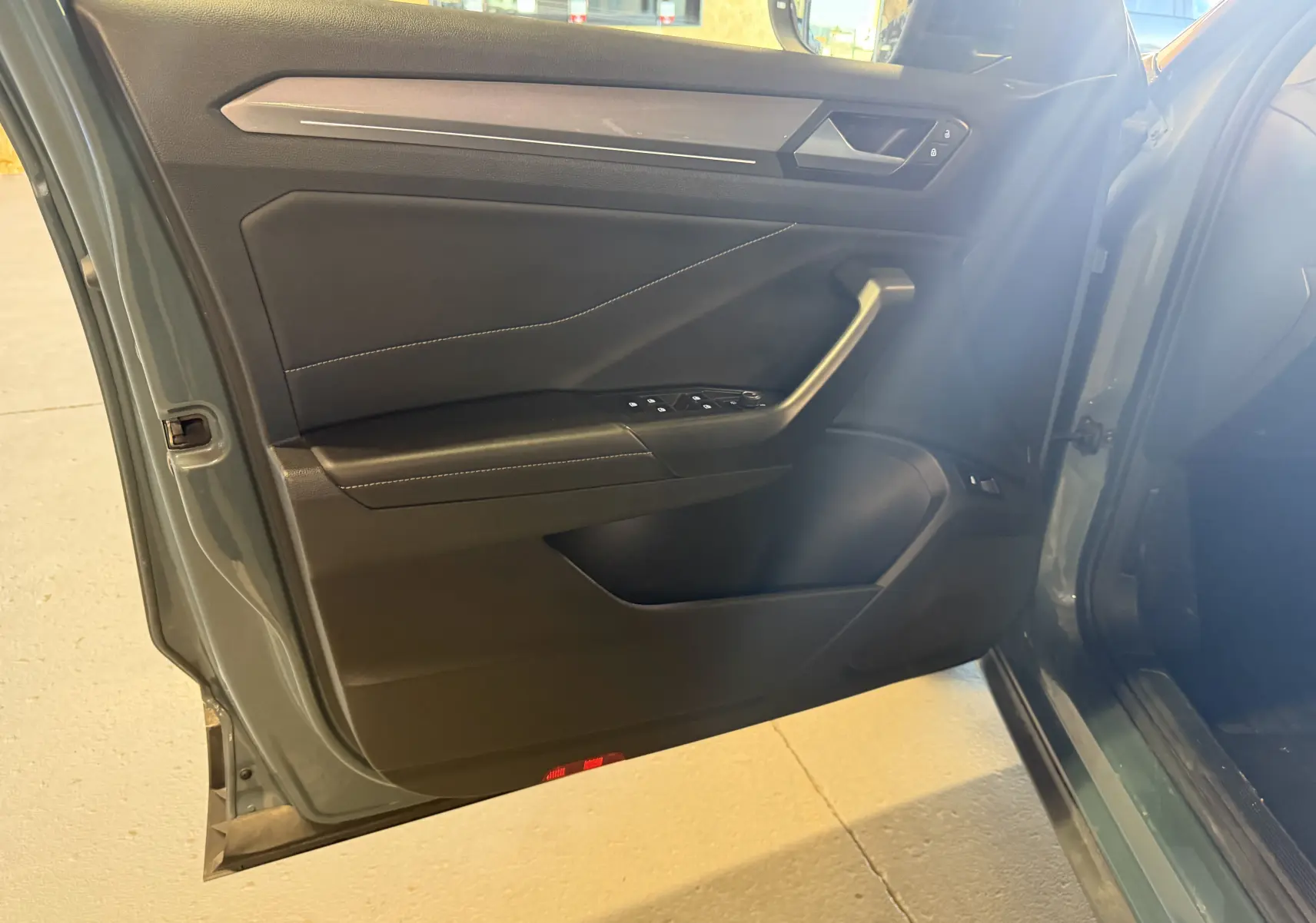 Vue rapprochée de la porte avant gauche bleu du Volkswagen T-Roc 2022, avec commandes de vitres et poignée intégrée.