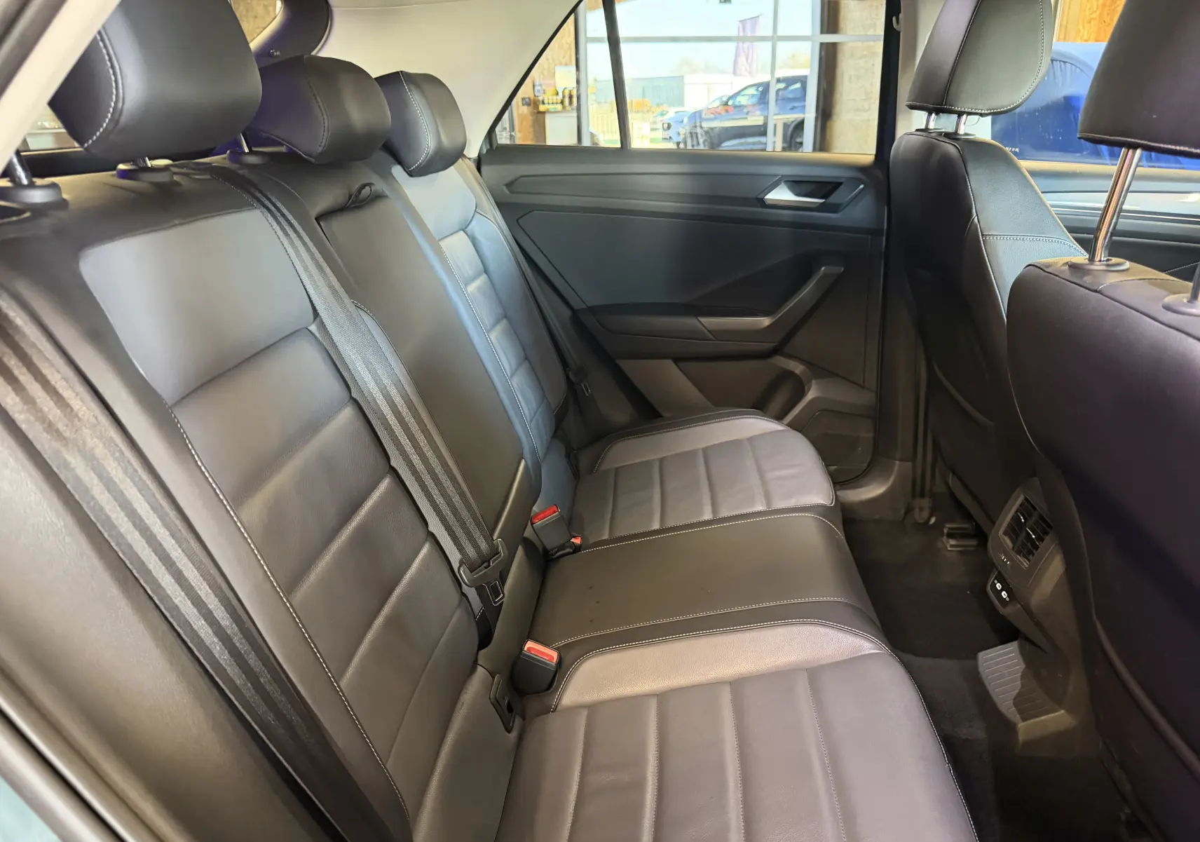 Vue intérieure côté droit des sièges arrière en cuir noir du Volkswagen T-Roc 2022, avec ceintures et appuie-têtes visibles.