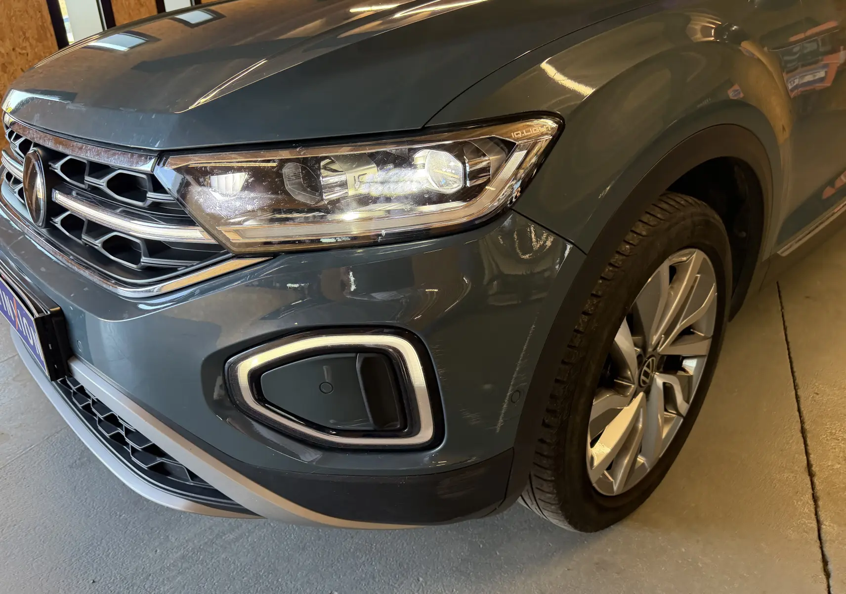 Gros plan sur l'avant droit bleu du Volkswagen T-Roc 2.0 TDI 150 DSG7 avec phares LED et jante alliage.