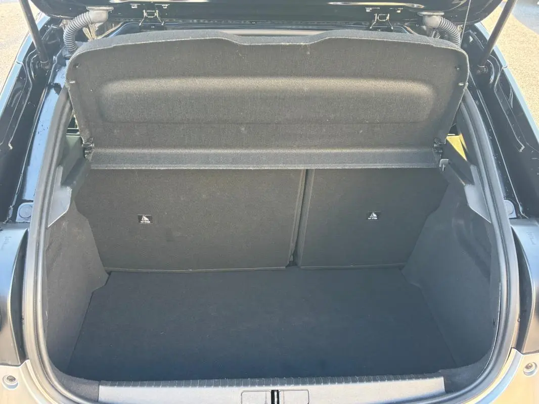 Coffre ouvert vu de l'arrière d'une Lancia Ypsilon gris 2025, montrant l'espace de chargement vide et la tablette arrière.