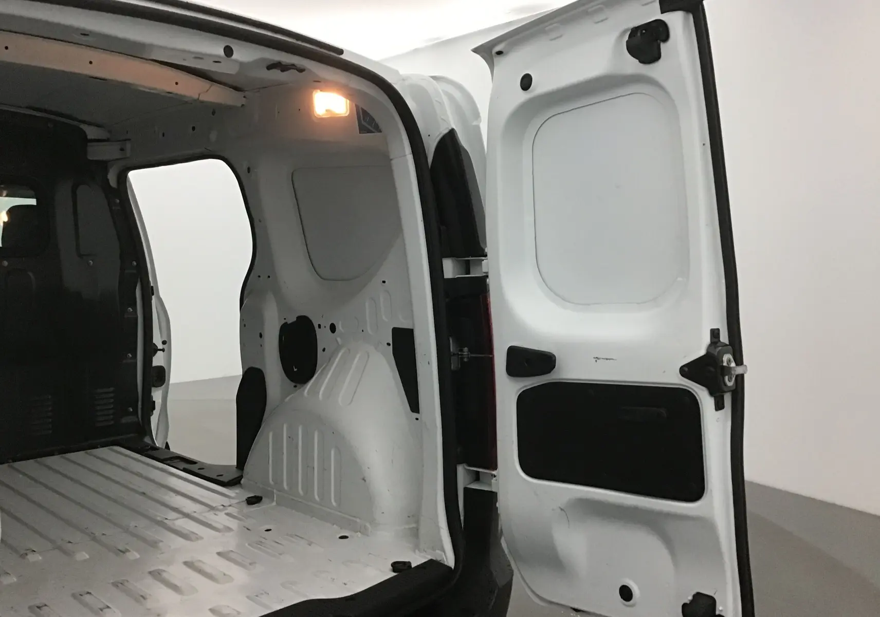 Intérieur du coffre blanc du Renault Express Van 2021, vue arrière avec porte ouverte et éclairage intérieur allumé.