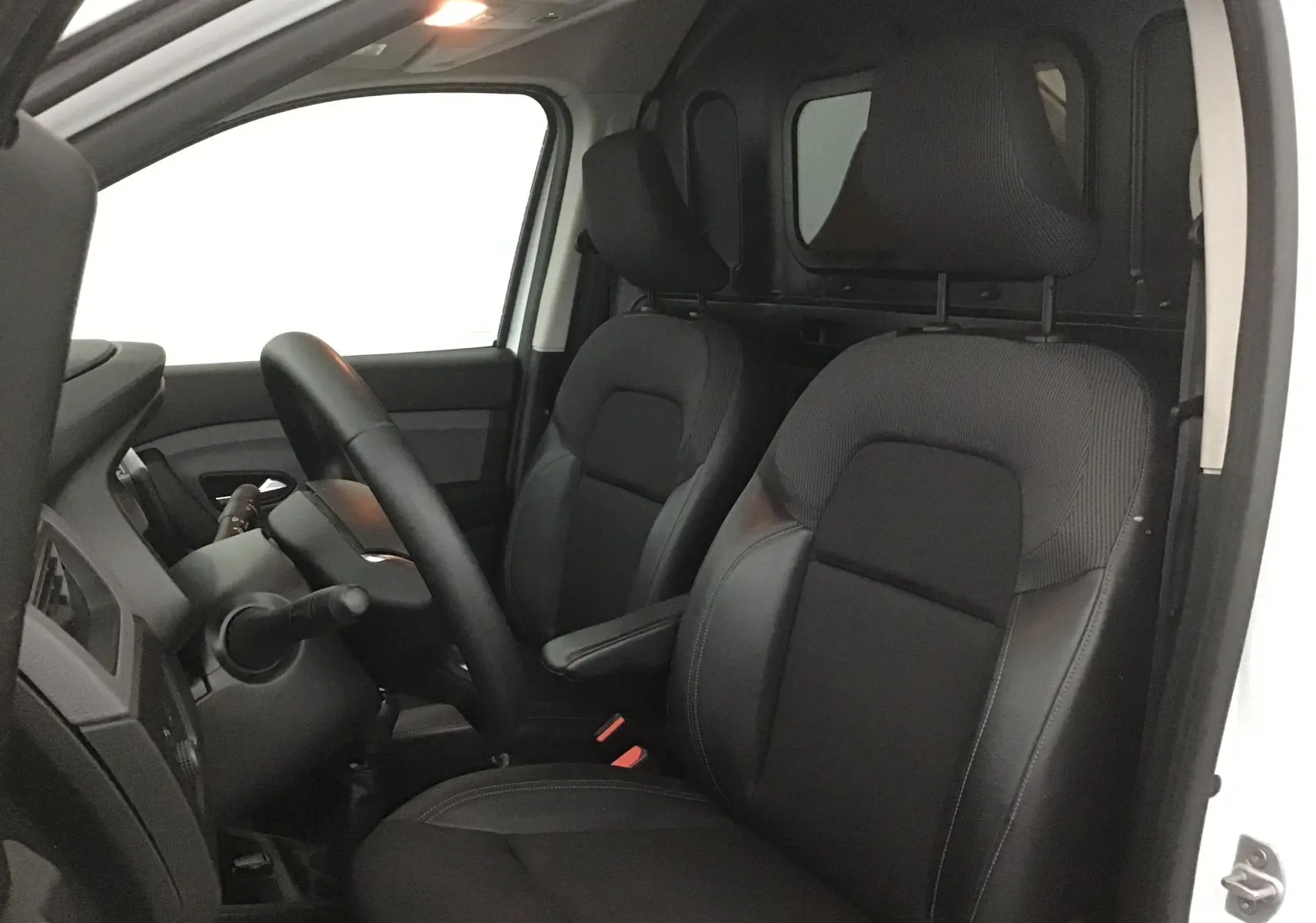 Vue intérieure côté conducteur du Renault Express Van blanc 2021, sièges noirs avec appuie-têtes et cloison arrière visible.