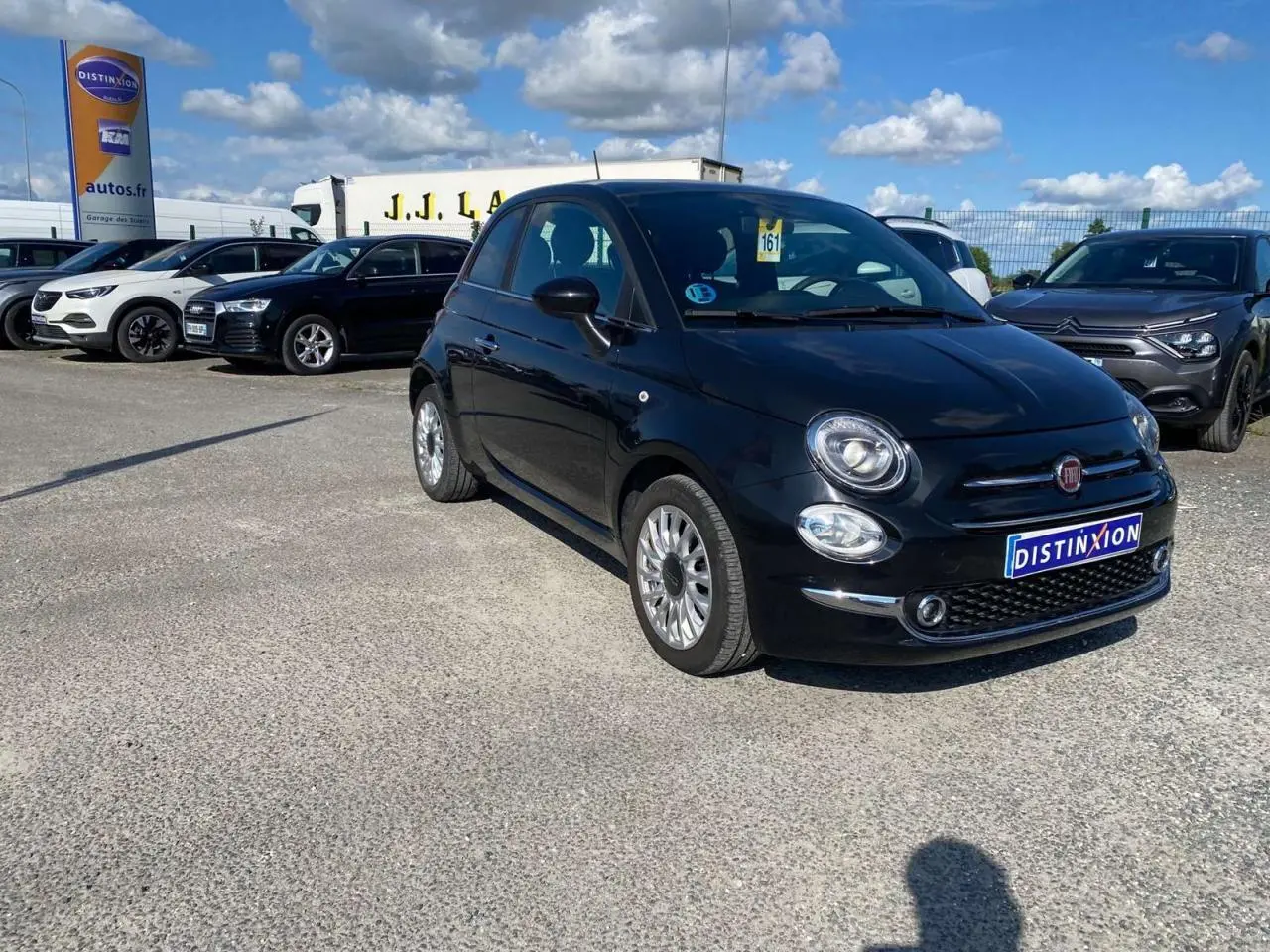Fiat 500 noire vue en 3/4 avant droit, avec jantes alliage 16'' Spider, stationnée sur un parking extérieur.