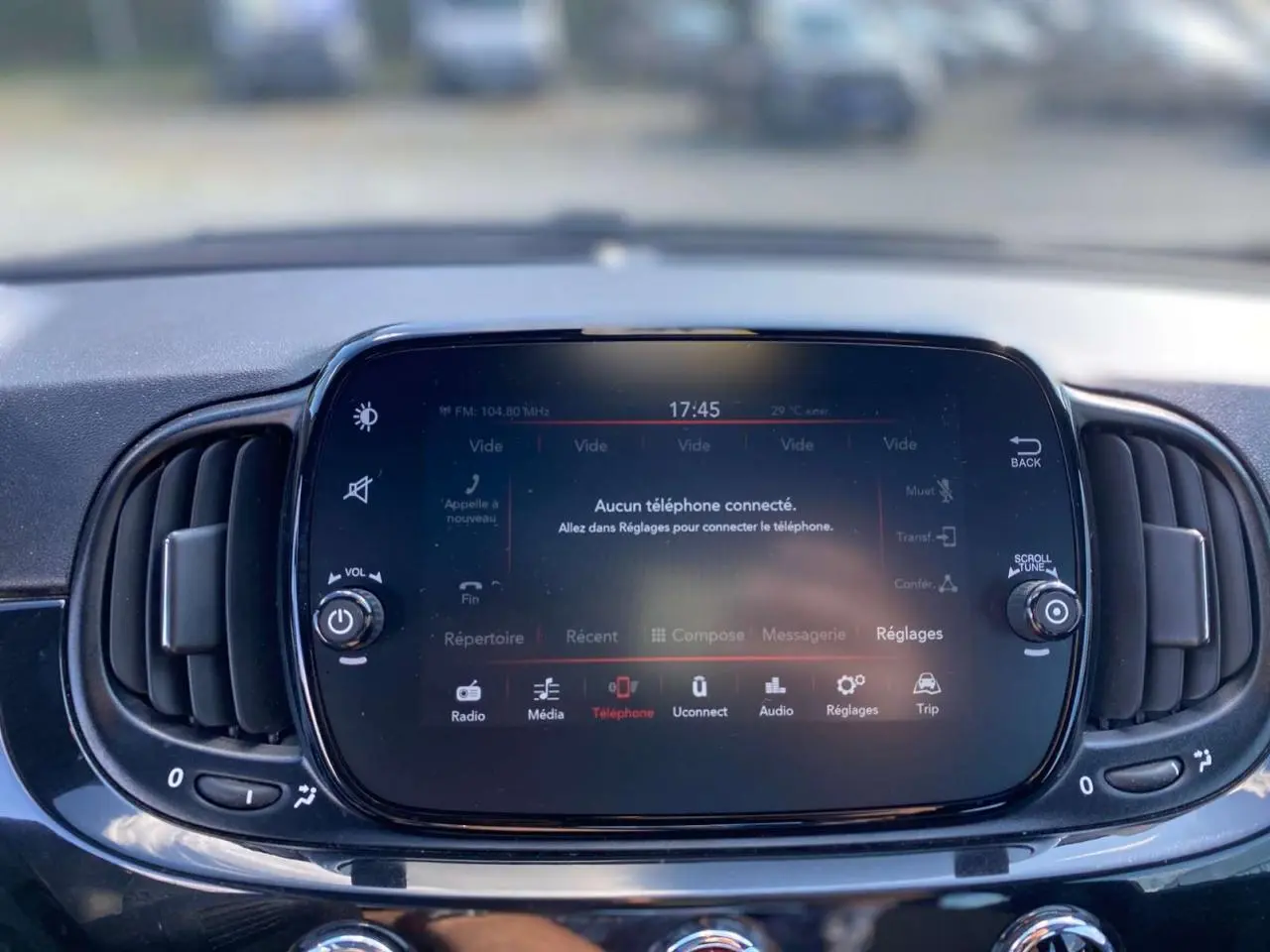 Écran tactile central du tableau de bord de la Fiat 500 noire 2024 avec commandes multimédia et ventilation intégrée.