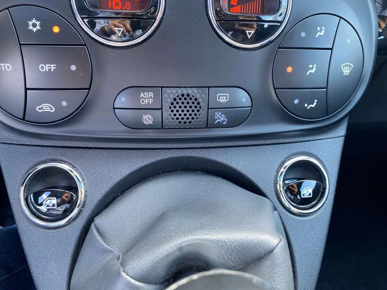 Gros plan sur la console centrale de la Fiat 500 noire 2024, montrant les commandes de climatisation et les boutons des vitres électriques.