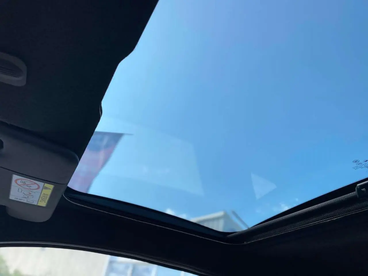 Toit vitré panoramique fixe de la FIAT 500 noire vue de l'intérieur vers le ciel bleu.