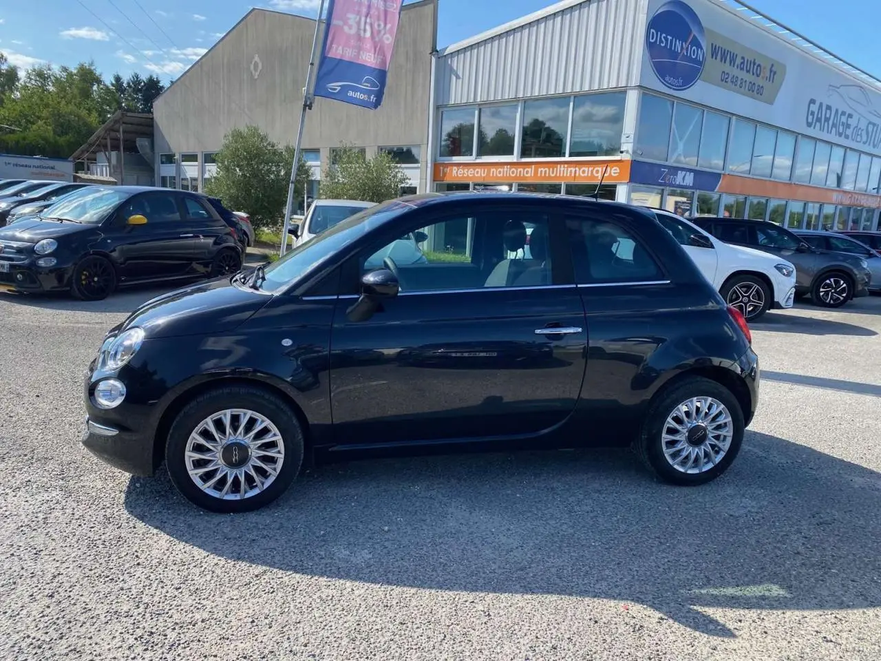 Profil latéral droit d'une FIAT 500 noire 2024 avec jantes alliage 16'' Spider, stationnée en extérieur.