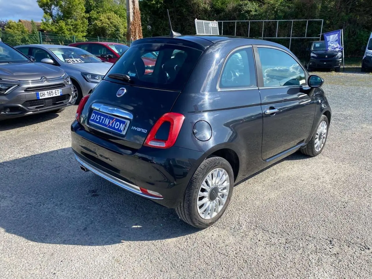 Fiat 500 noire vue 3/4 arrière droit, avec jantes alliage et toit vitré panoramique fixe.