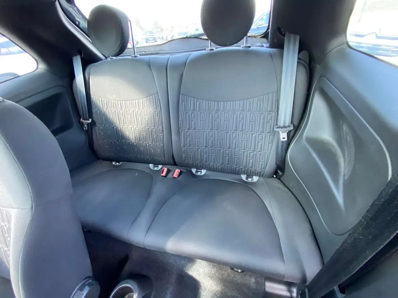 Vue intérieure arrière de la banquette noire de la Fiat 500 2024 avec motifs FIAT embossés sur les dossiers.