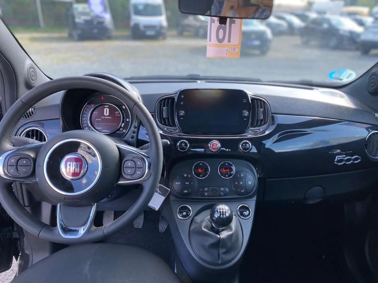 Vue intérieure du tableau de bord noir brillant de la Fiat 500 2024 avec volant multifonction et levier de vitesse manuel.