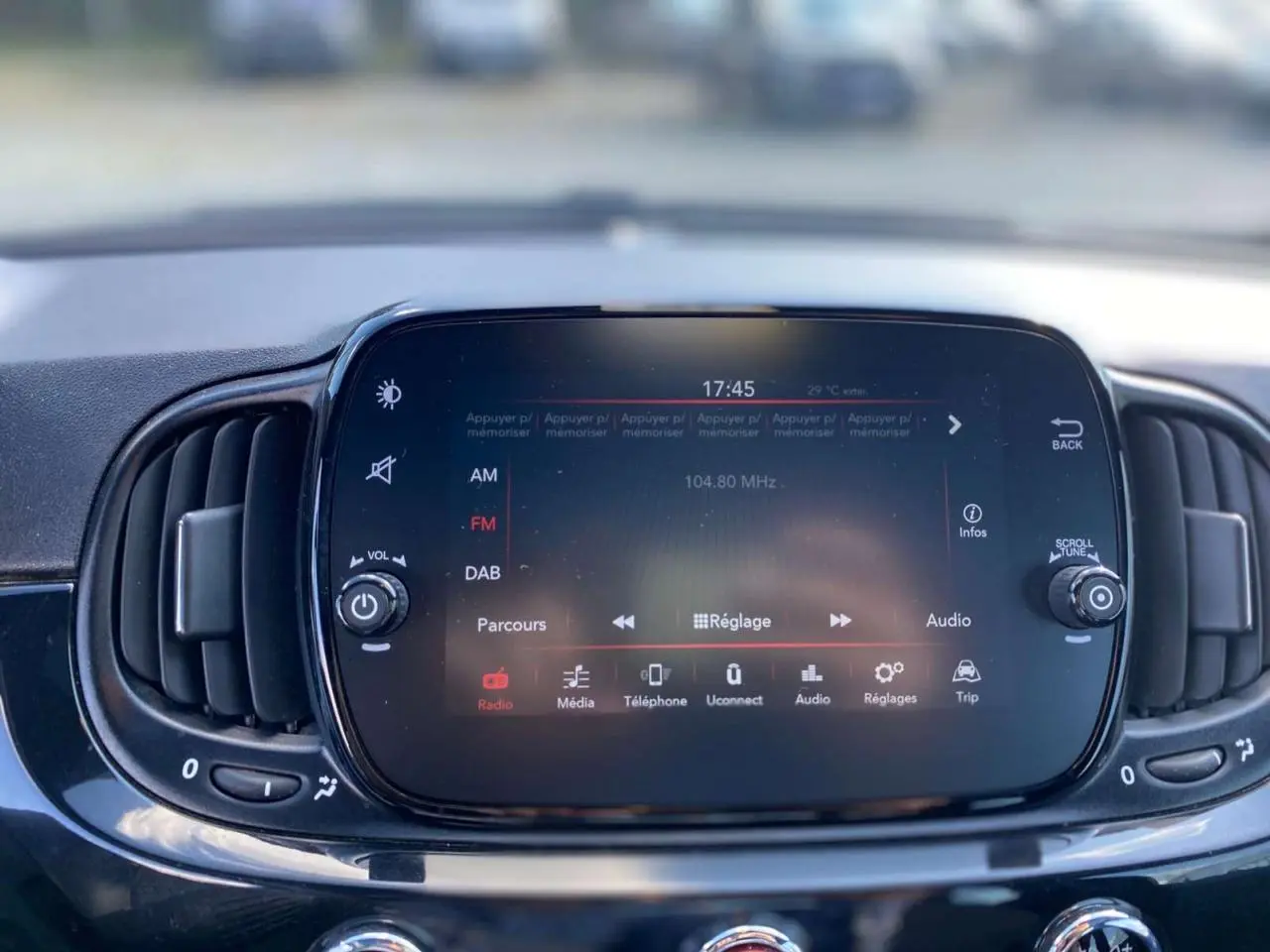 Écran tactile central du tableau de bord du Fiat 500 noir 2024, affichant les réglages radio et multimédia.