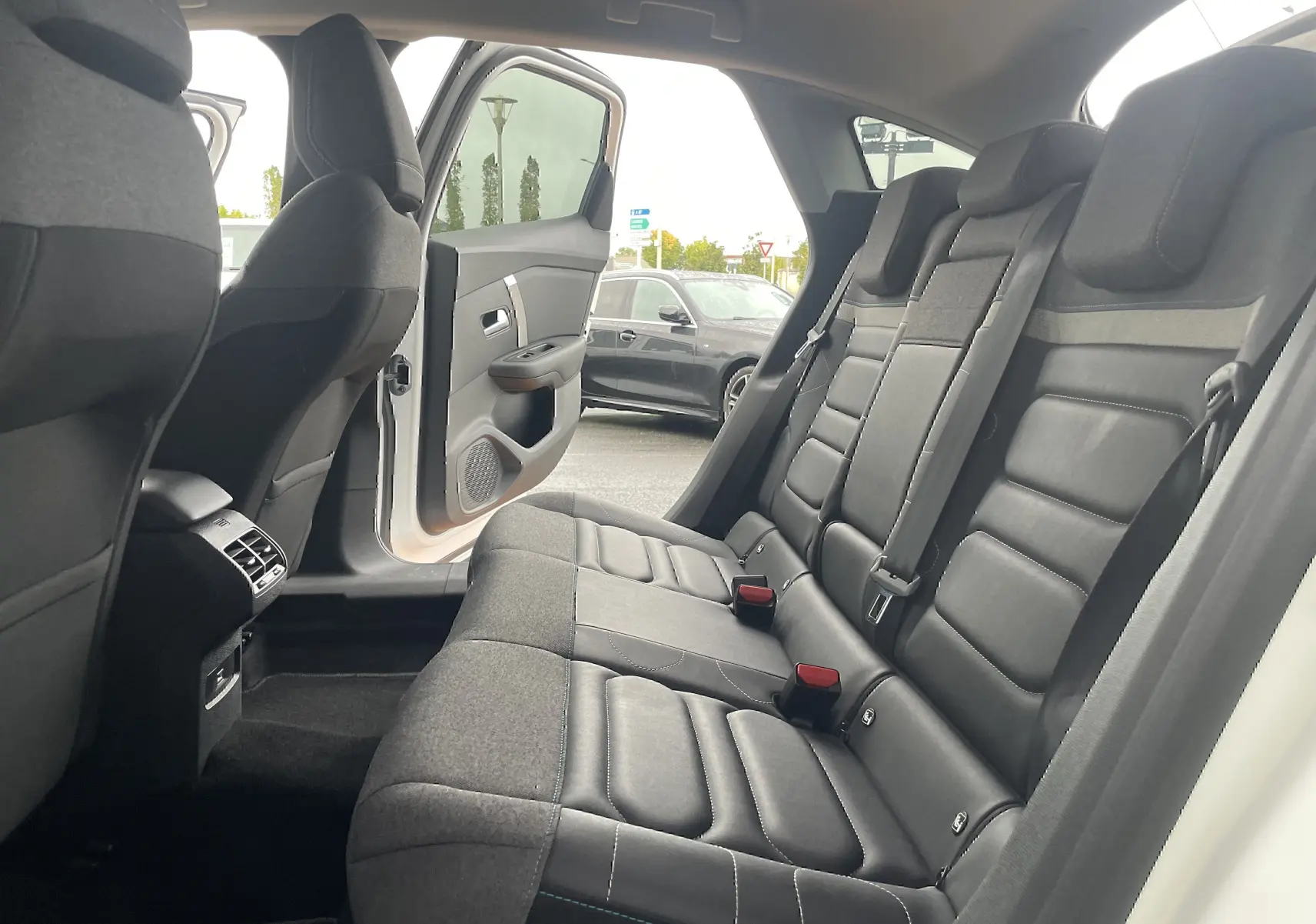 Vue intérieure arrière droite d'une Citroën C4 blanche 2022, sièges arrière en tissu gris noir avec ceintures de sécurité visibles.
