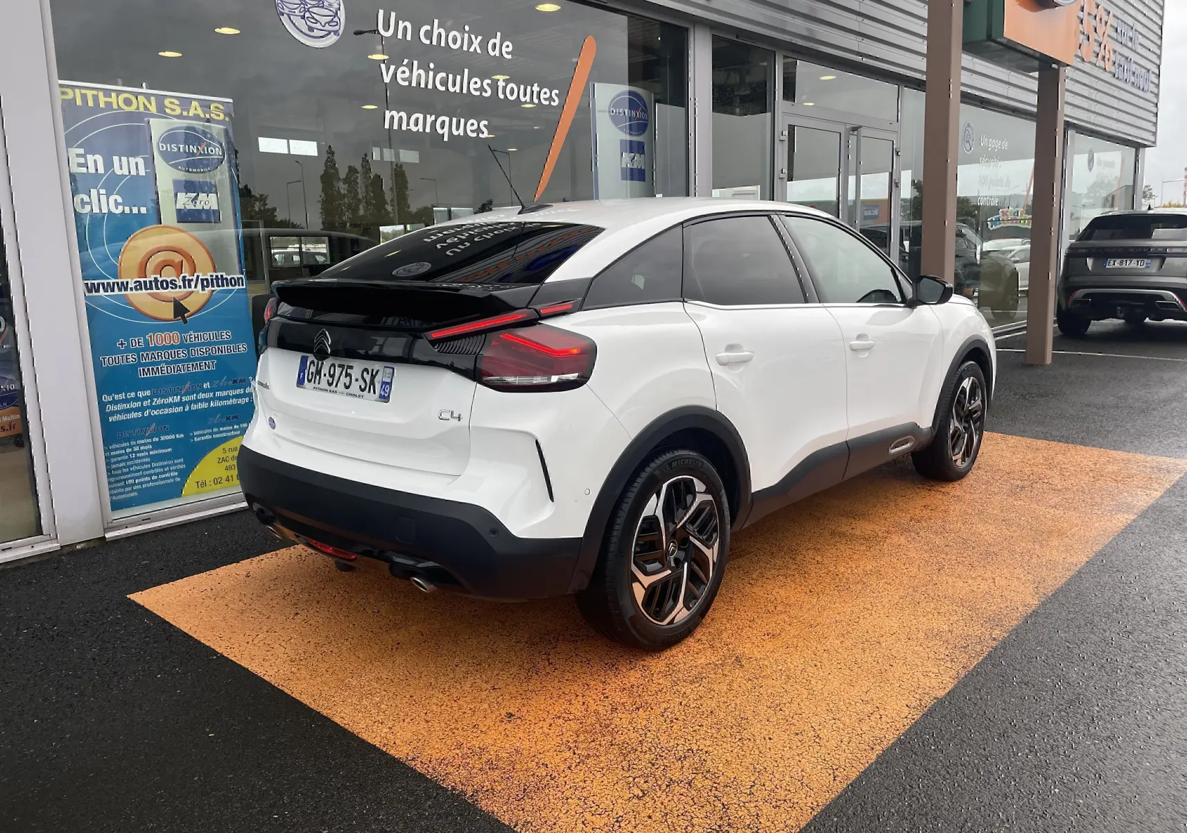 Vue 3/4 arrière droite d'une Citroën C4 blanche 2022 avec toit noir et feux arrière LED distinctifs.