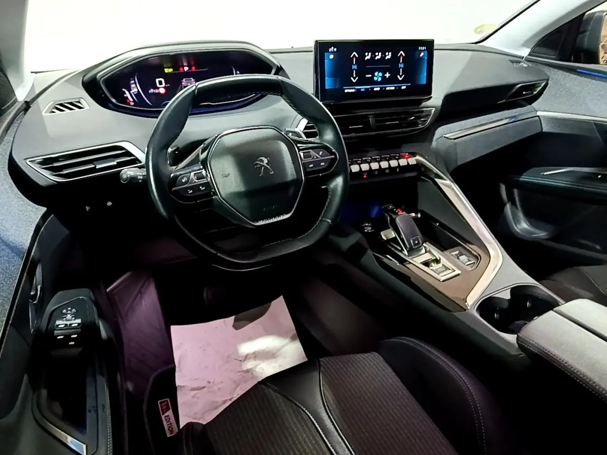 Vue intérieure avant du Peugeot 3008 noir 2022, volant cuir multifonctions et écran tactile central lumineux.