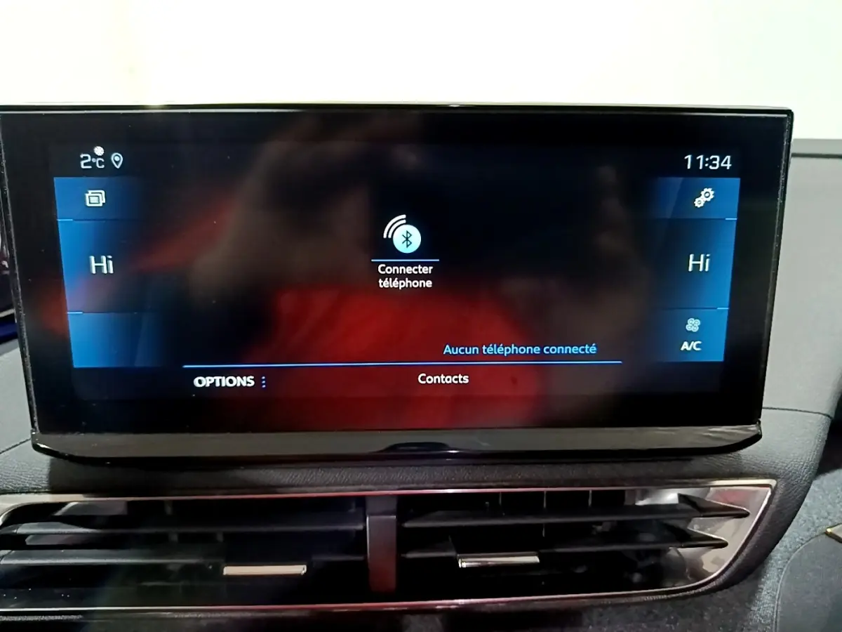 Écran tactile central du tableau de bord du Peugeot 3008 noir, affichant la connexion Bluetooth et la climatisation.