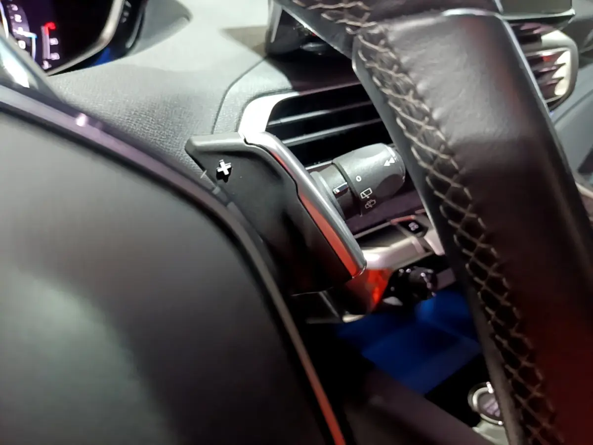 Gros plan sur le volant cuir noir et la commande de palette de changement de vitesse du Peugeot 3008 2022.