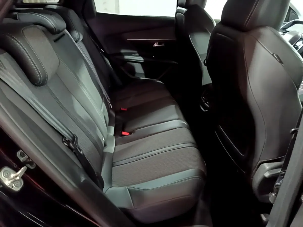 Vue intérieure côté arrière gauche du Peugeot 3008 noir, montrant la banquette arrière en tissu et cuir avec ceintures de sécurité.