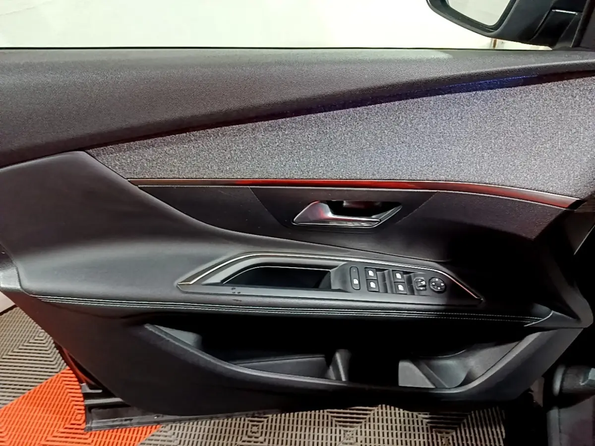 Vue du panneau de porte avant gauche noir avec commandes électriques et poignée chromée sur Peugeot 3008 2022.