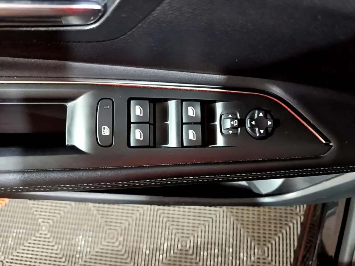 Gros plan sur les commandes de lève-vitres et rétroviseurs côté gauche, avec finition cuir noir et surpiqûres blanches.