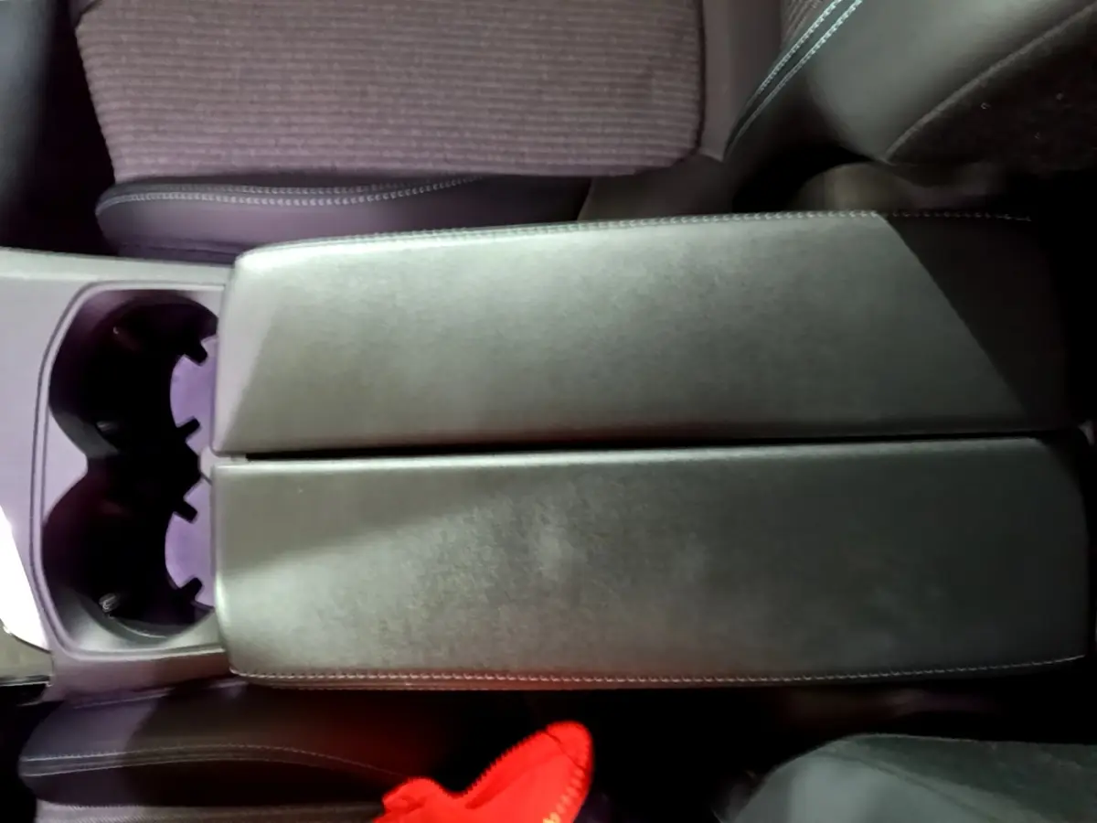 Vue plongeante sur l'accoudoir central en cuir noir et porte-gobelets du Peugeot 3008 noir, version Allure Pack 2022.