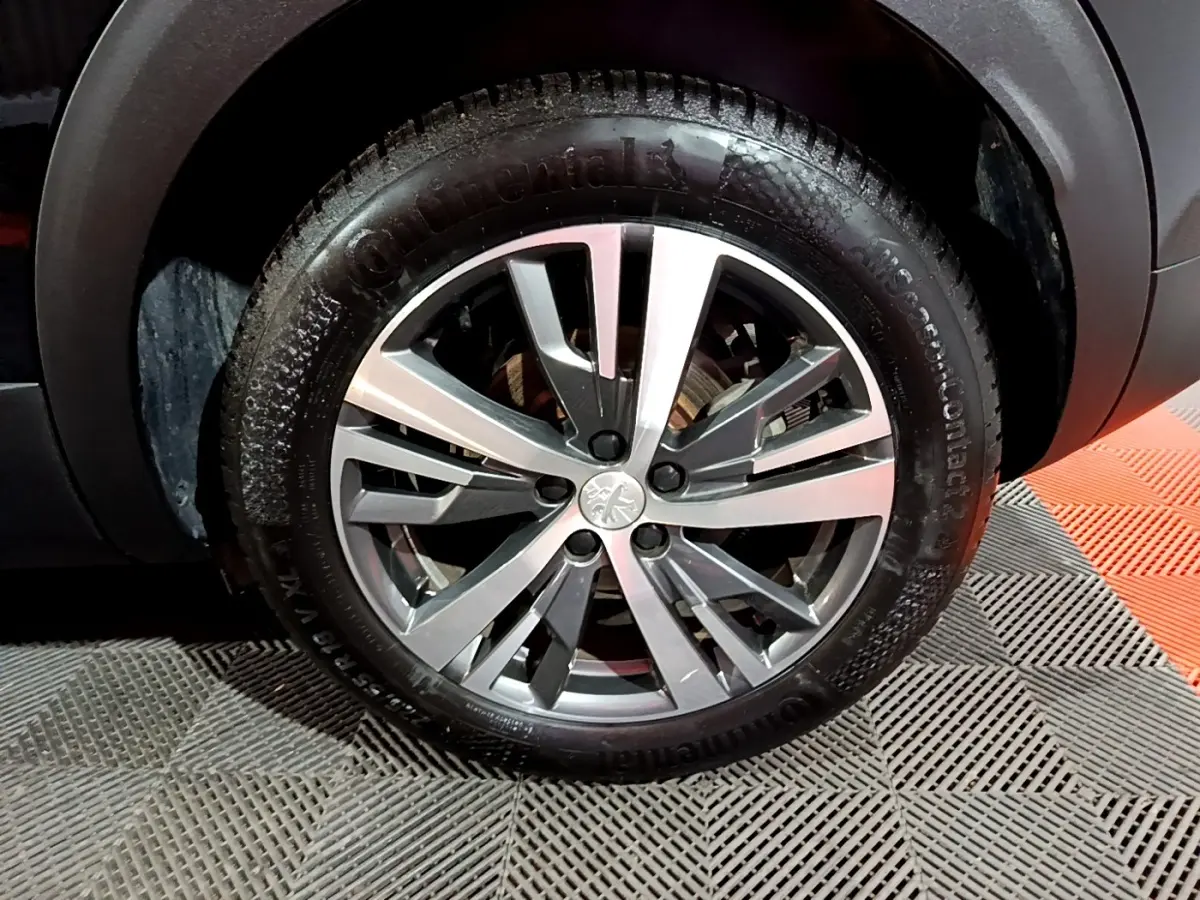 Gros plan sur la roue avant droite du Peugeot 3008 noir, jante alliage argentée à design moderne.