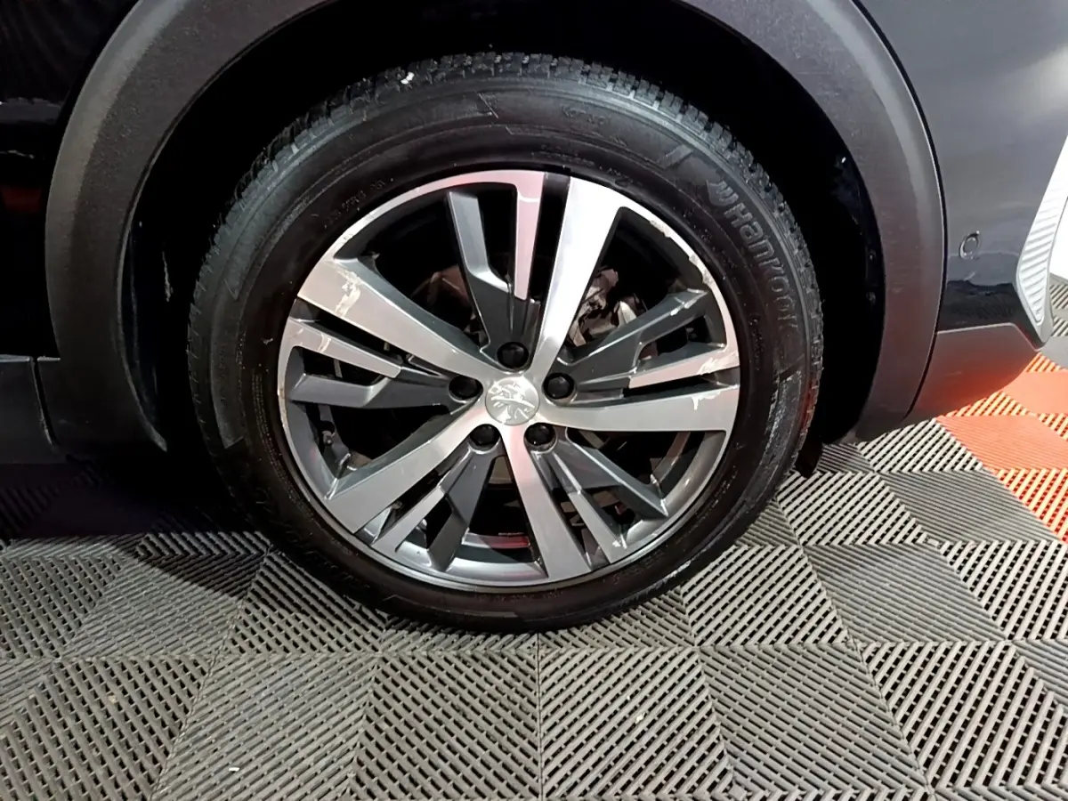 Gros plan sur la roue avant droite du Peugeot 3008 noir, avec jante alliage à design moderne et pneu Hankook.