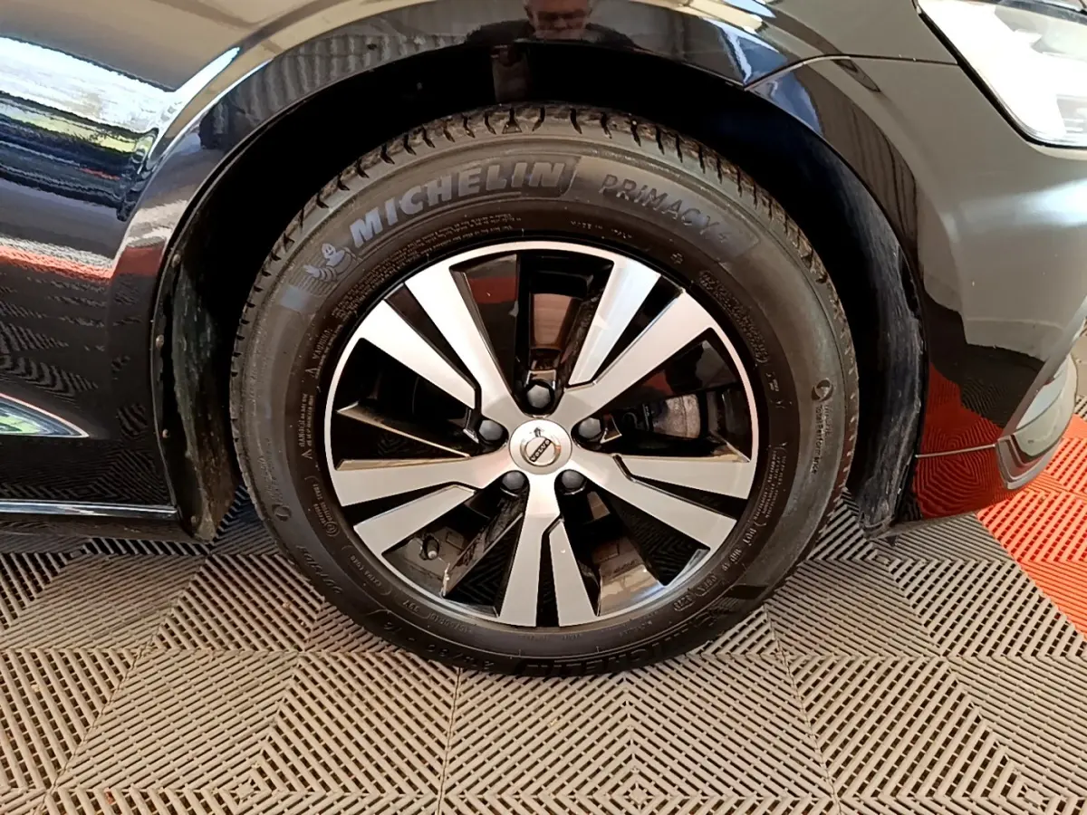 Gros plan sur la roue avant gauche noire d'une Volvo V60 2020 avec jante alliage bicolore et pneu Michelin.
