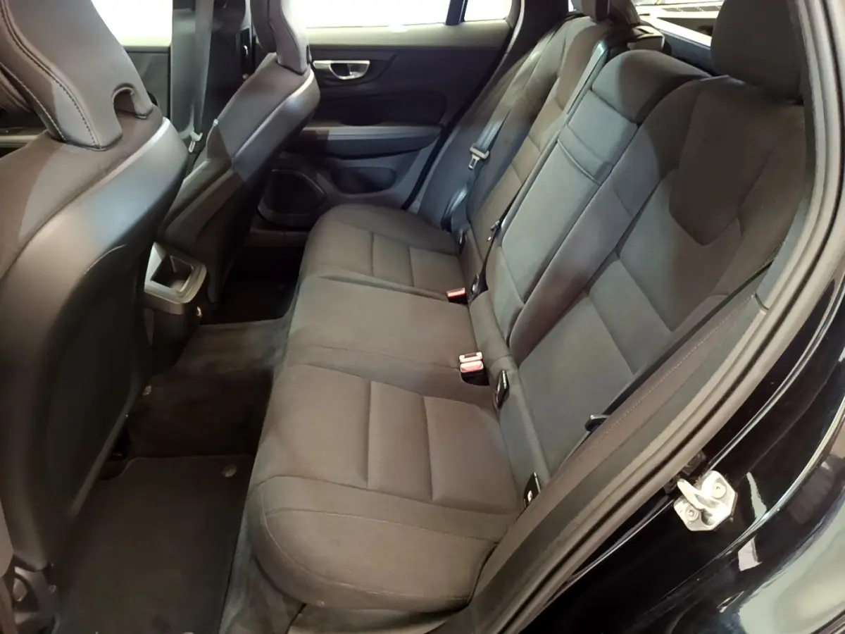 Vue intérieure côté droit montrant la banquette arrière noire de la Volvo V60 avec sièges en tissu et ceintures de sécurité.