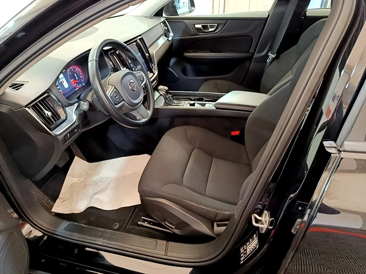Intérieur avant droit de la Volvo V60 noire 2020, montrant siège conducteur, volant cuir et tableau de bord digital.